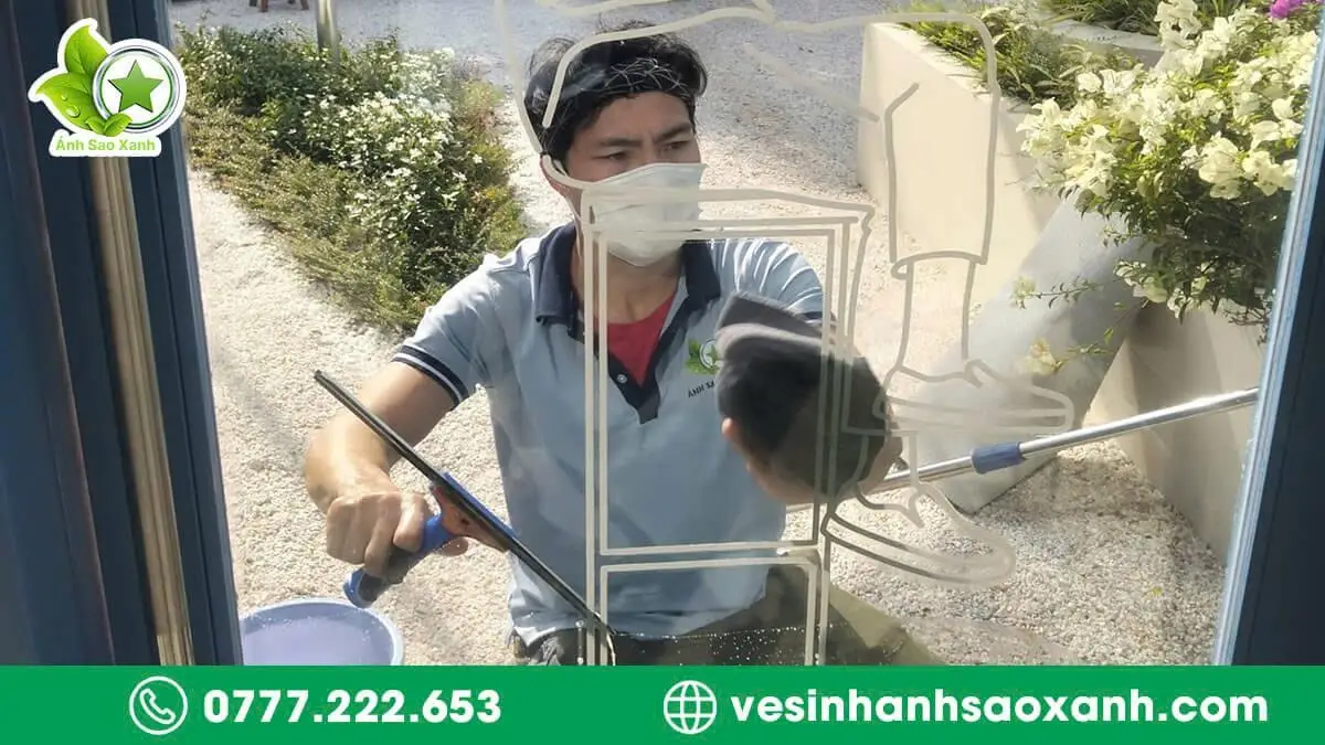 Nhân viên Ánh Sao Xanh đang lau kính nhà ở TPHCM bằng dụng cụ chuyên dụng