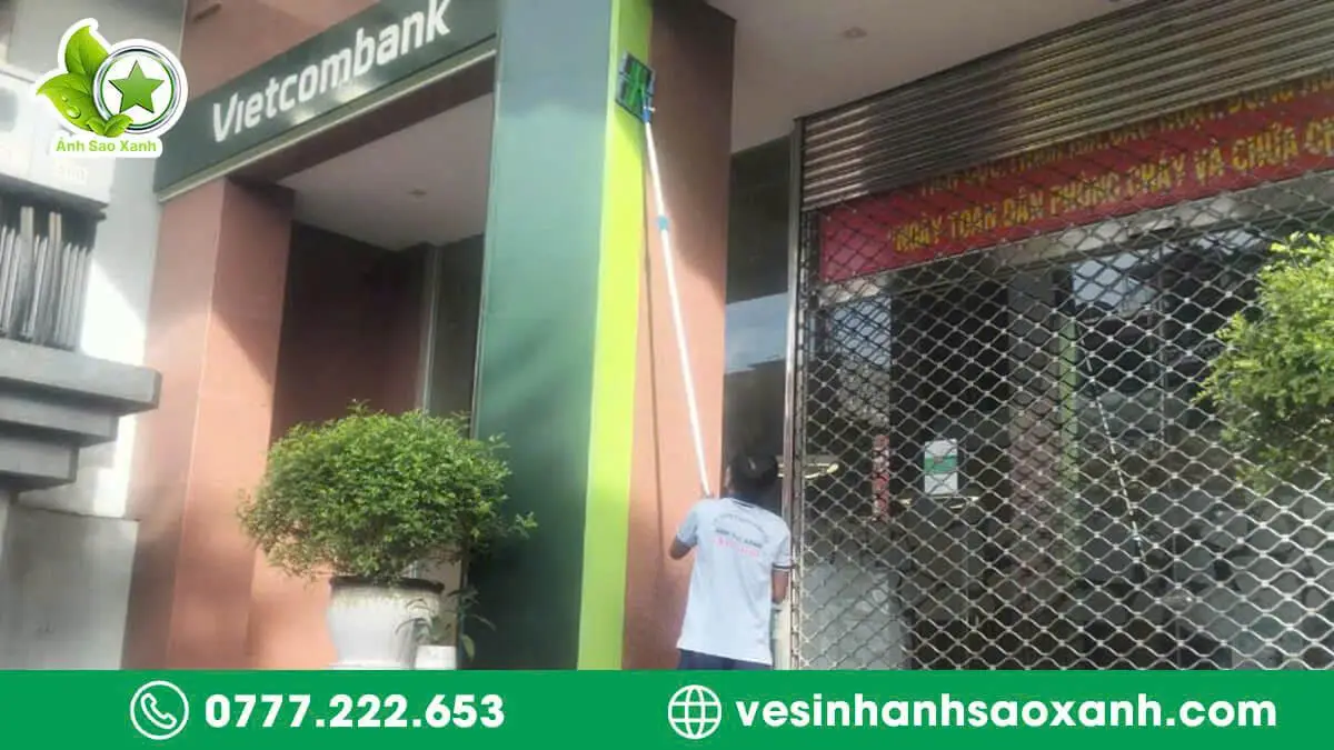 Kỹ thuật viên Ánh Sao Xanh vệ sinh bảng hiệu alu tại ngân hàng ở TPHCM bằng dụng cụ chuyên dụng.