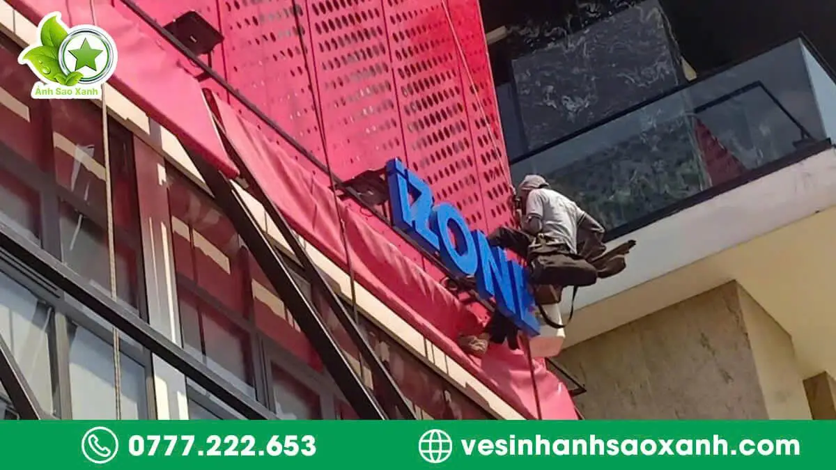 Kỹ thuật viên Ánh Sao Xanh vệ sinh bảng hiệu hiflex ngoài trời bằng dây an toàn trên cao tại TPHCM.