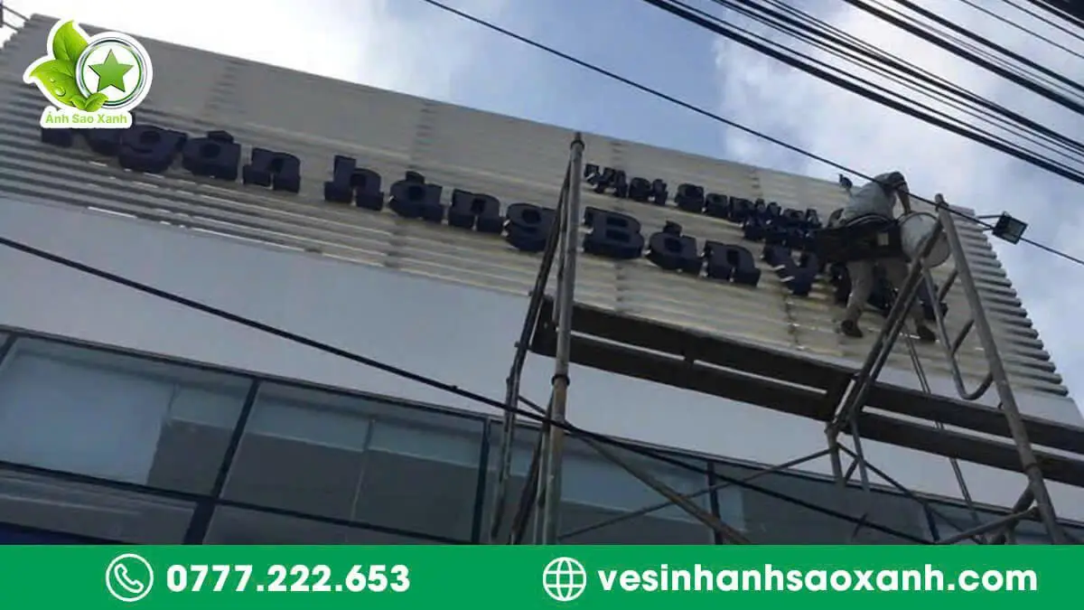 Kỹ thuật viên Ánh Sao Xanh vệ sinh bảng hiệu LED hộp đèn tại mặt tiền ngân hàng ở TPHCM bằng giàn giáo an toàn.