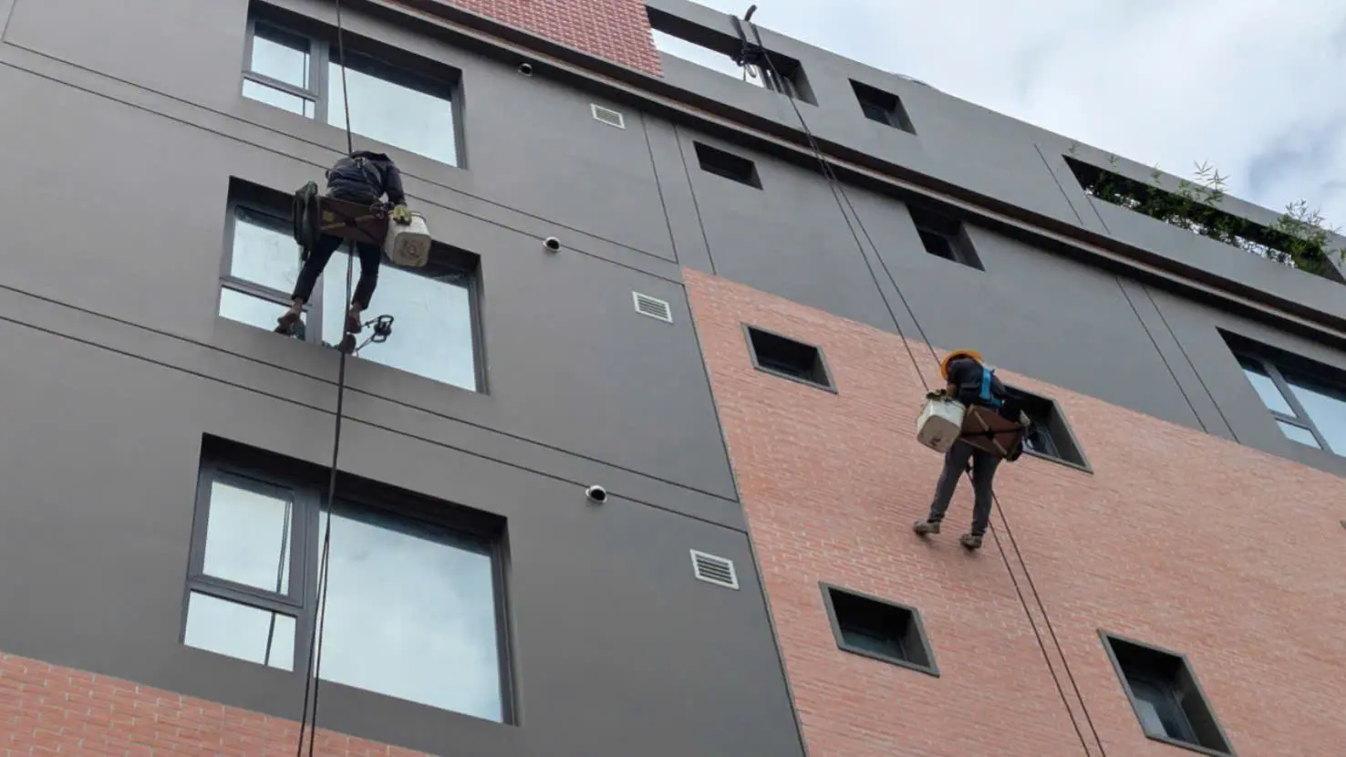 Nhân viên lau kính tòa nhà tại TPHCM bằng phương pháp đu dây