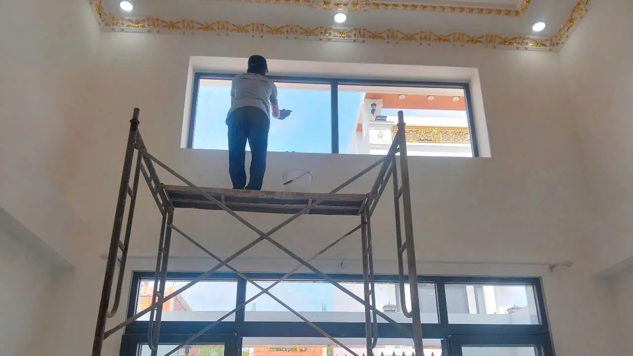 Nhân viên lau kính mặt tiền tại TPHCM bằng giàn giáo