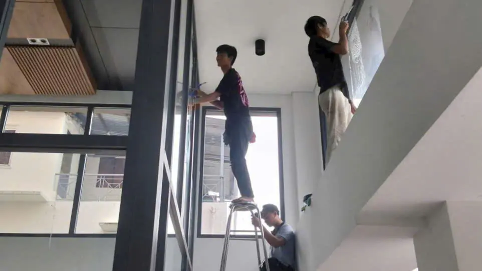 Nhân viên lau kính văn phòng tại TPHCM bằng cây nối dài