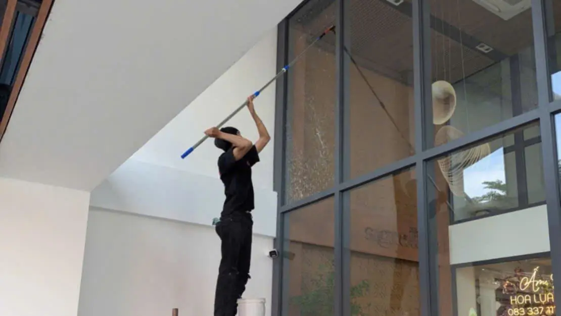 Nhân viên lau kính văn phòng tại TPHCM bằng thang nhôm