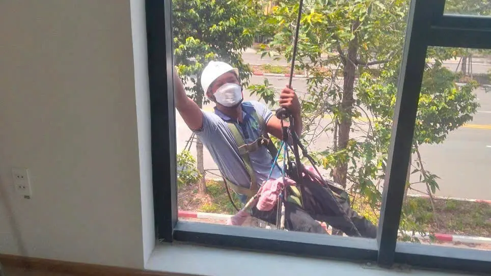 Nhân viên lau kính tòa nhà tại TPHCM bằng dây đu