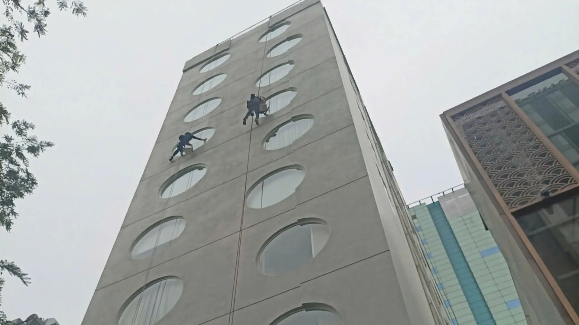 Nhân viên lau kính tòa nhà tại TPHCM bằng dây đu