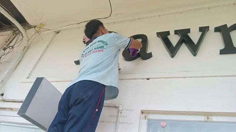 Hình ảnh nhân viên vệ sinh bảng hiệu tại Quận 1